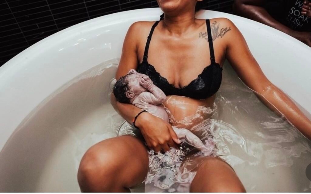 A mother holding her newborn in a birthing tub after a peaceful water birth.