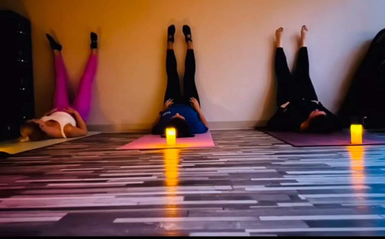 Pregnant women practicing prenatal yoga with calming candlelight in a Charleston yoga studio.